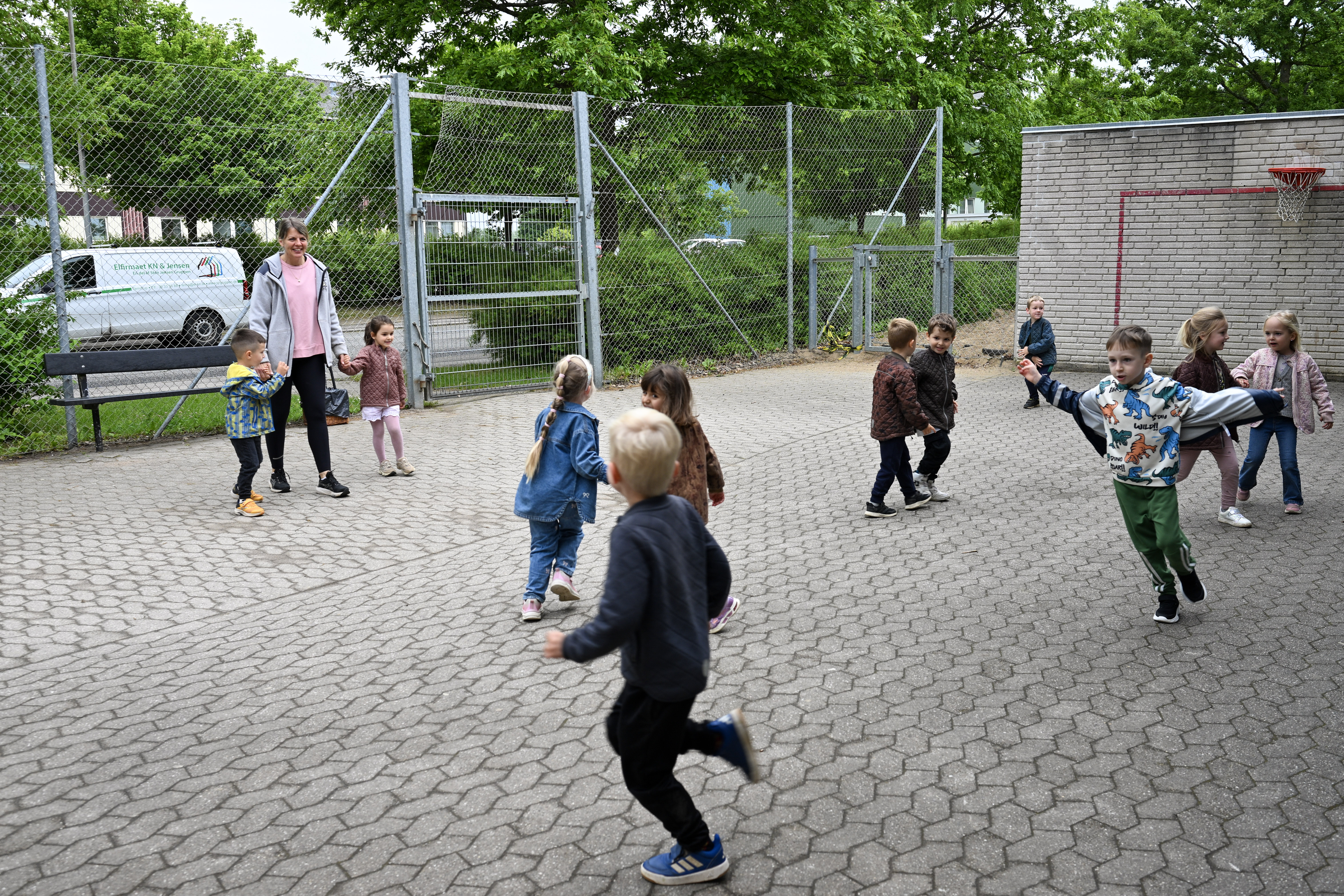 Voksen og børn leger på legepladsen