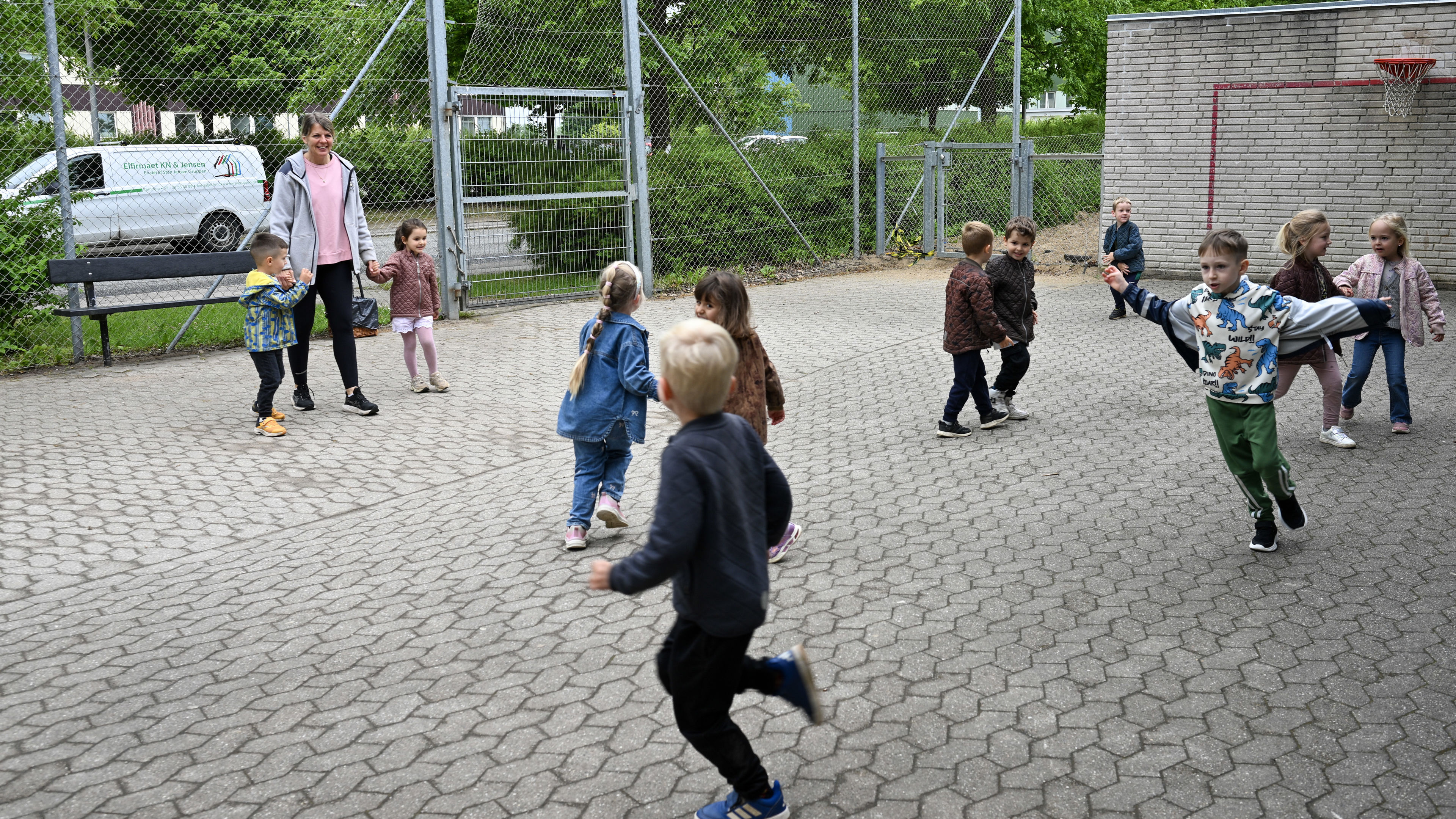 Voksen og børn leger på legepladsen